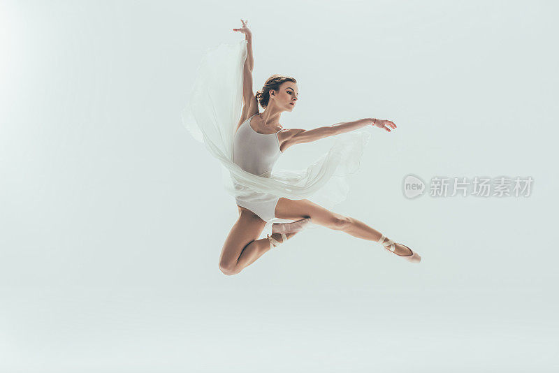 年轻优雅的芭蕾舞女演员在白色连衣裙跳在工作室，孤立在白色