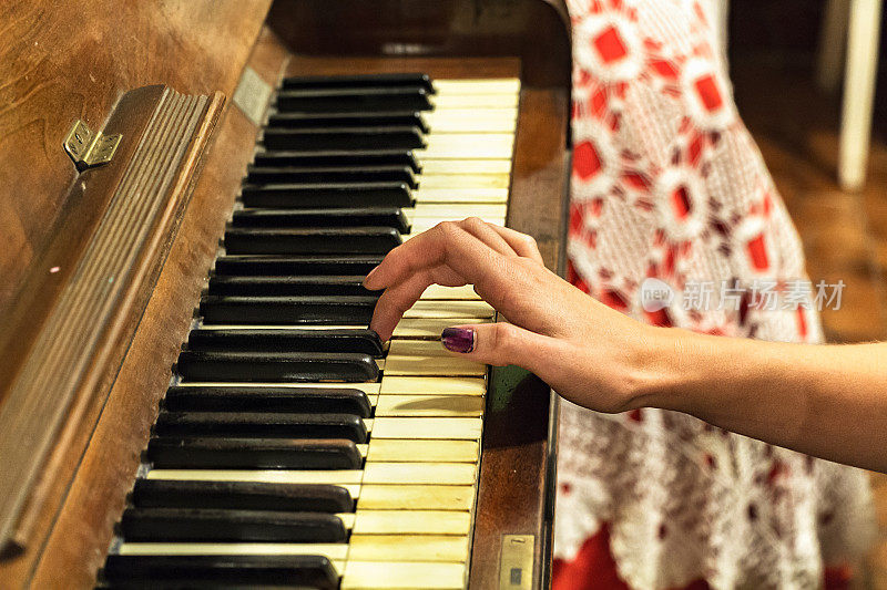 一只女人的手在弹奏一架老式钢琴。