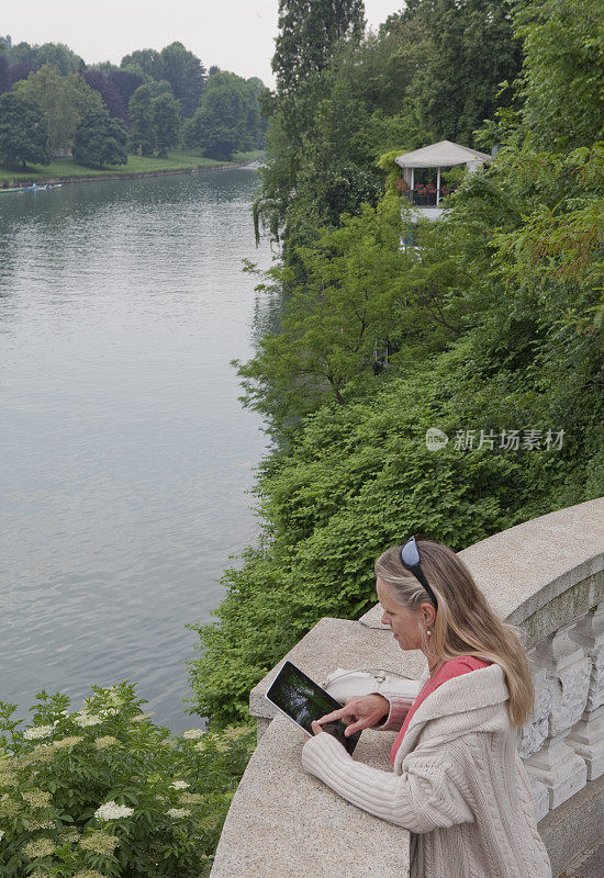 一名女子在河上的阳台上用ipad