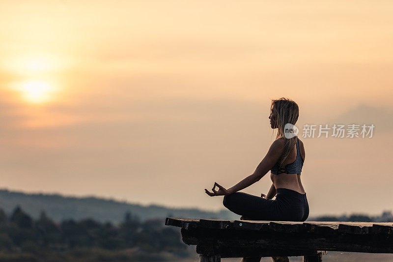 健康和运动的年轻女子在湖边做瑜伽