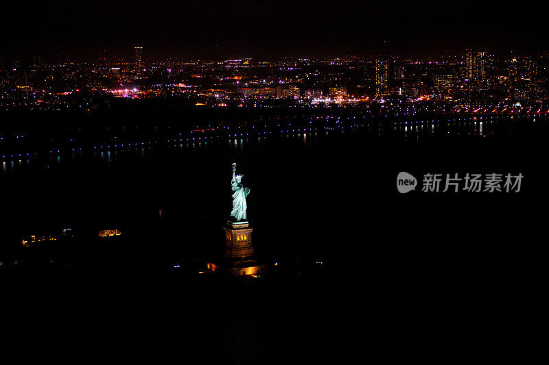 自由女神像和自由女神在夜晚的纽约上湾闪闪发光