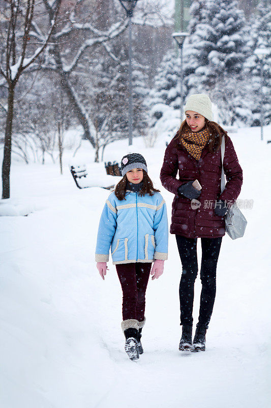 两姐妹走在白雪覆盖的森林里