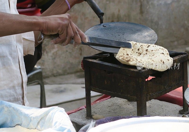 在印度德里，印度街头小吃摊贩正在用小麦面团做烤饼