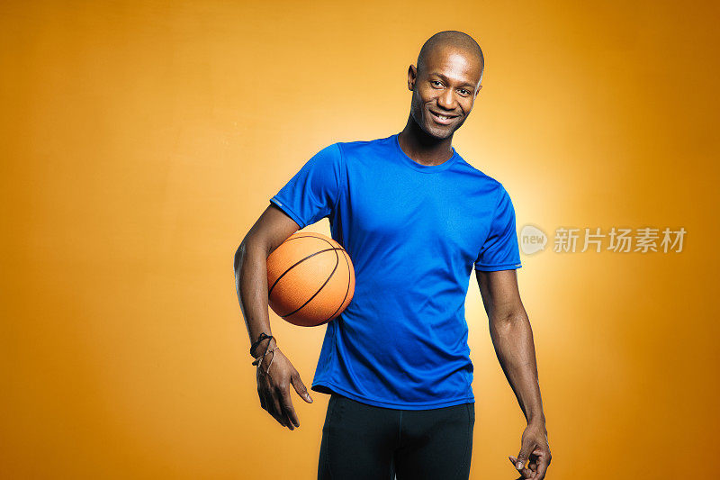 成熟的秃头黑人男子篮球运动员酷肖像与橙色背景