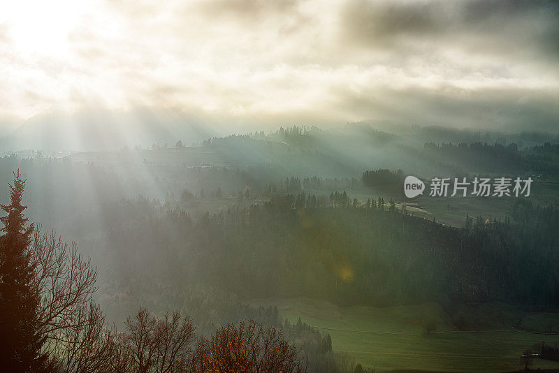 阳光透过高山的云层照耀着大地