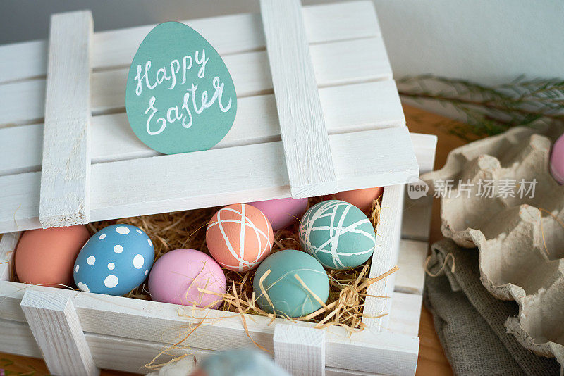 特写白色木箱与彩色复活节彩蛋与创意设计在干草放在桌子上