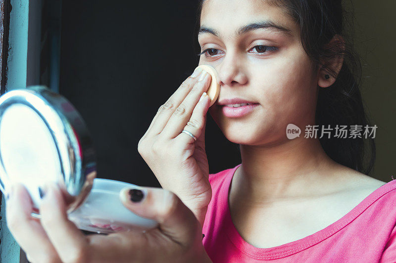 女孩用化妆粉扑擦干粉底的肖像