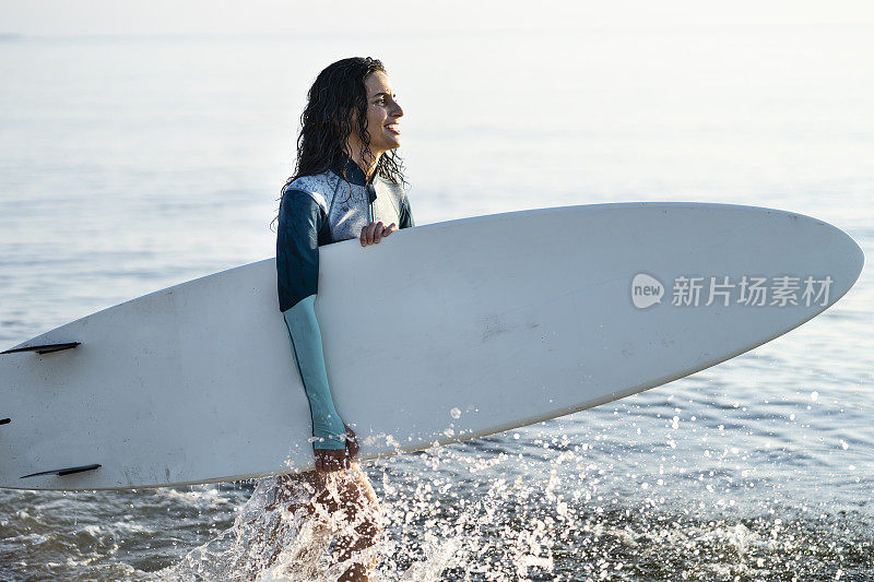 拿着冲浪板在水里走的女人