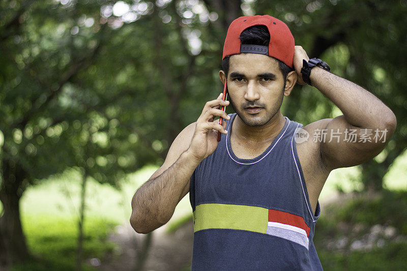 年轻的印度运动员在操场或公园慢跑后使用智能手机