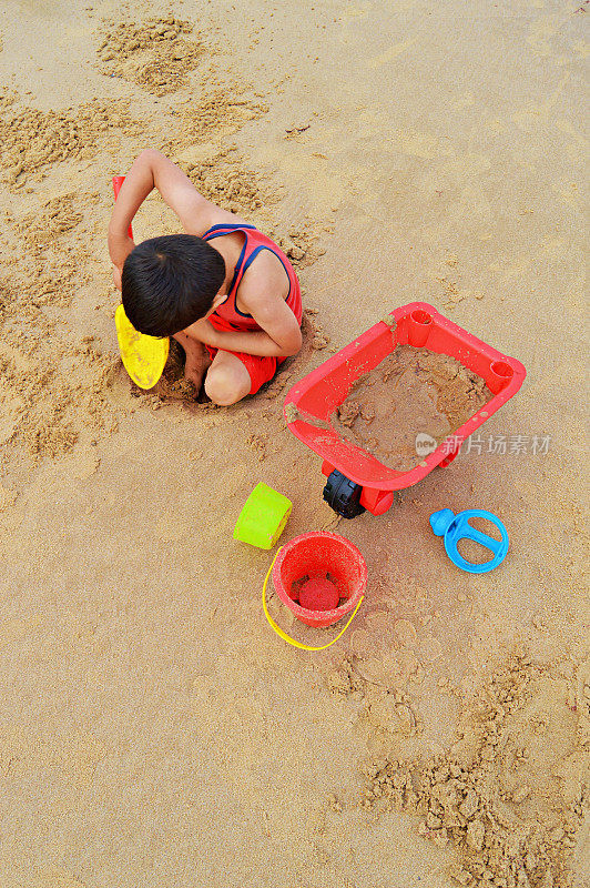 一个小的在沙滩上玩沙滩玩具。