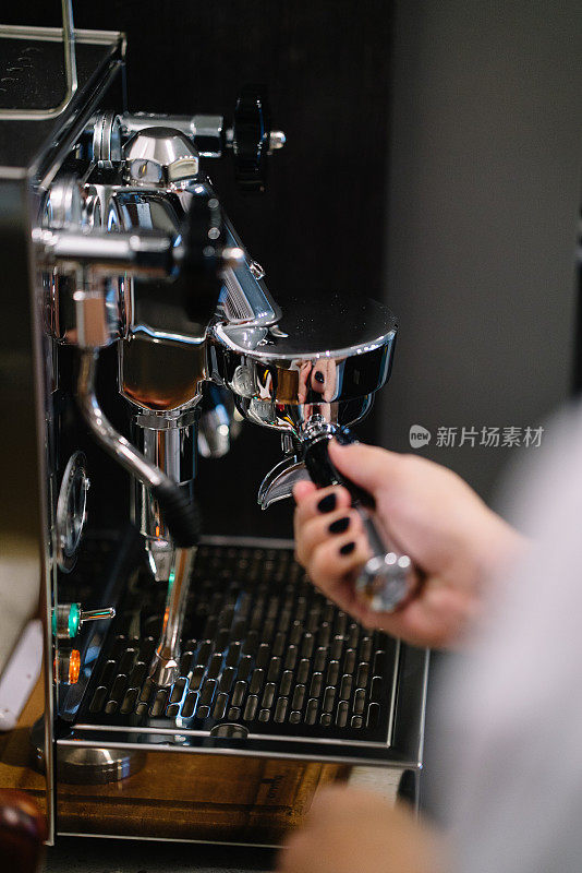 一个家庭咖啡师将一个便携式滤网放入咖啡机