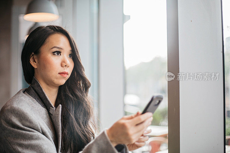 一名年轻女子在咖啡店里使用手机