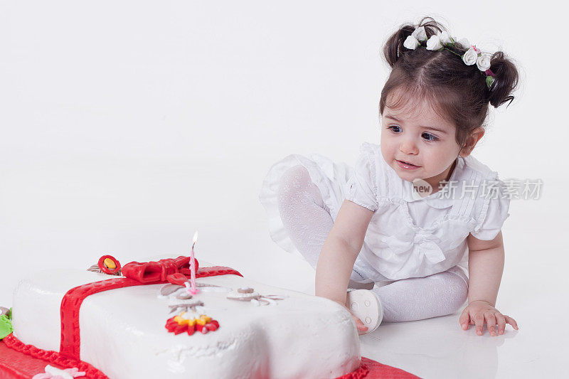 小女孩坐在生日蛋糕旁边