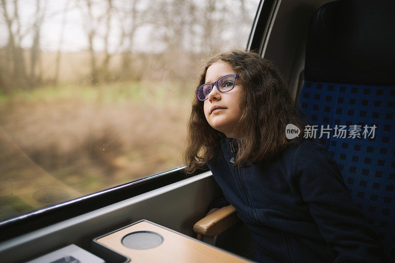 可爱的小女孩透过火车窗户欣赏美丽的风景