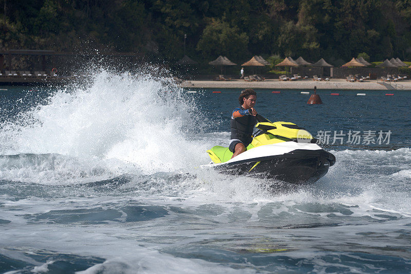 在蓝色的日子里，一名男子驾驶着黄色摩托艇在碧蓝的海面上滑行