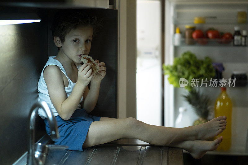 可爱的男孩在冰箱前吃东西