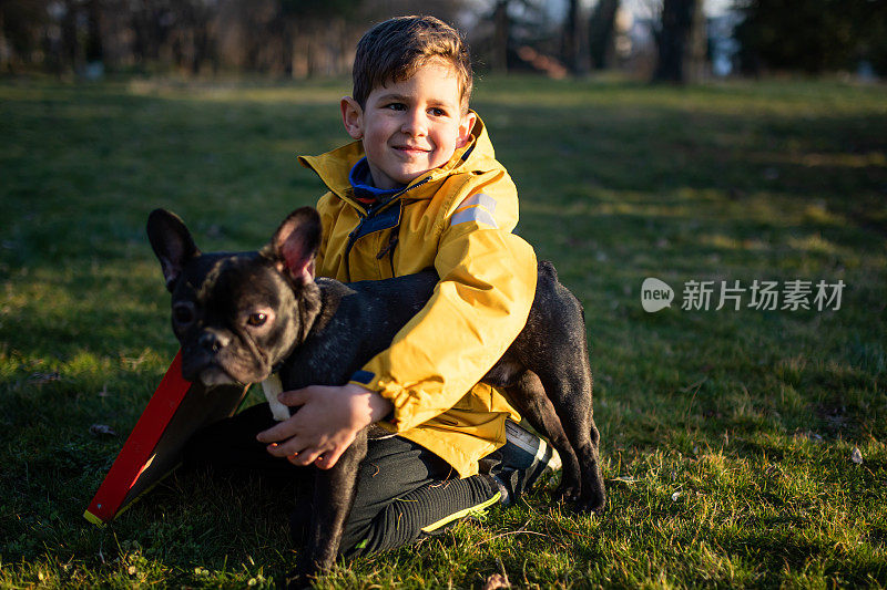 一个可爱的小男孩抱着一只法国斗牛犬