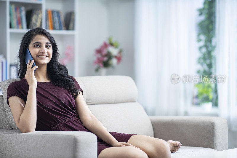 年轻女子坐在家里的沙发-库存照片