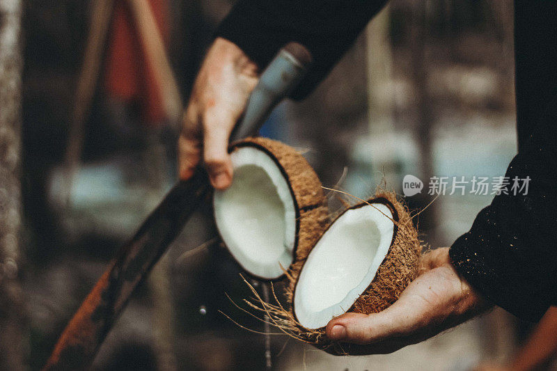 一个男人正在用大砍刀切开椰子