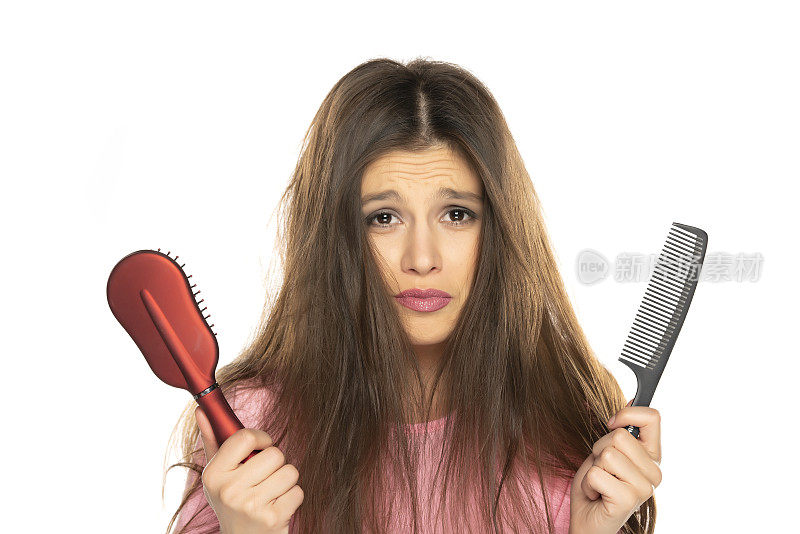 一个年轻的神经质的女人拿着梳子和梳子凌乱的头发