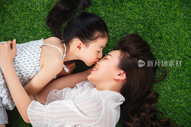 草地上小女孩亲吻母亲