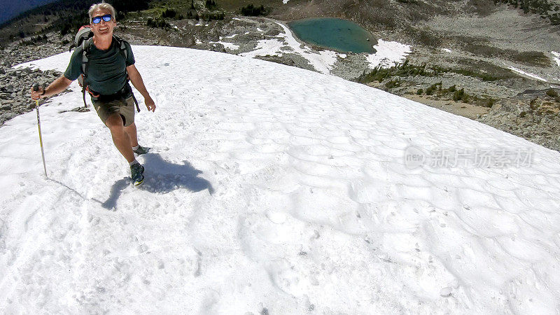 徒步旅行者沿着积雪的山坡跑下去