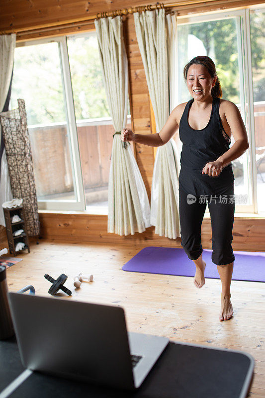 一个女人在家里对着笔记本电脑锻炼