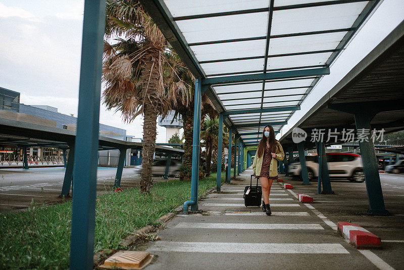 一名年轻女子在机场停车场戴着防护面罩