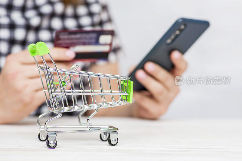 女人手里拿着信用卡，用智能手机在网上购物。女性使用智能手机支付信用卡。在线购物。