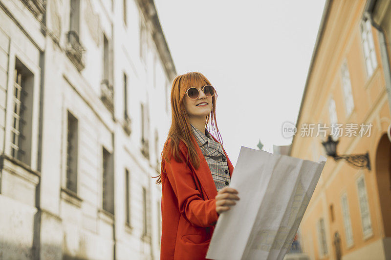 女旅行者在街上看城市地图。旅行，乐趣，度假的概念。