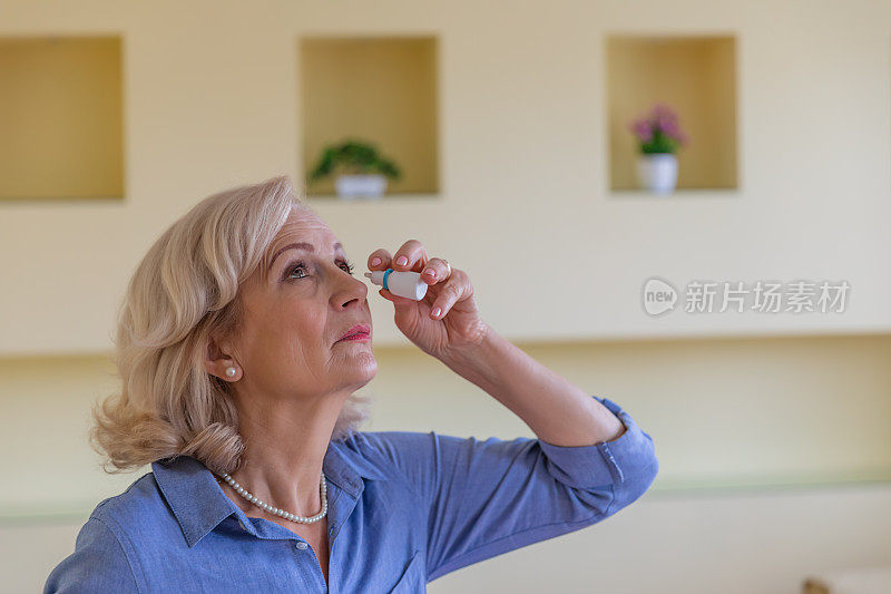 一位老年妇女用眼药水改善视力。