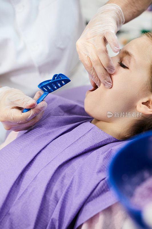 牙齿矫正医生在牙科诊所取小女孩的牙印的特写。