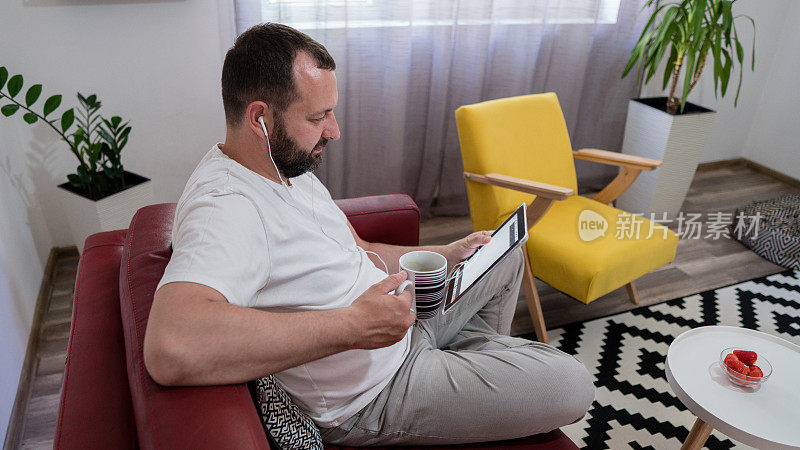 男人戴着耳机在家里用数码平板电脑