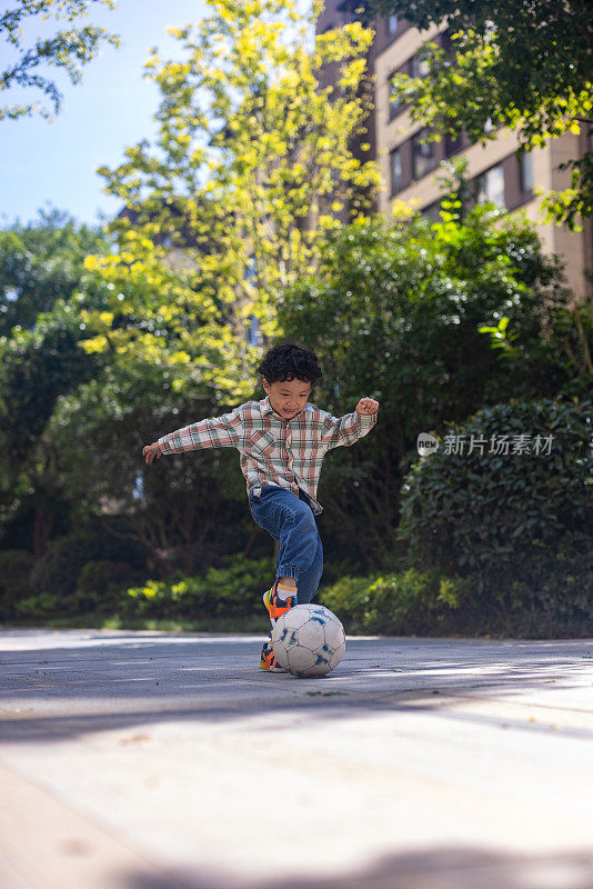 一个小男孩在院子里踢足球