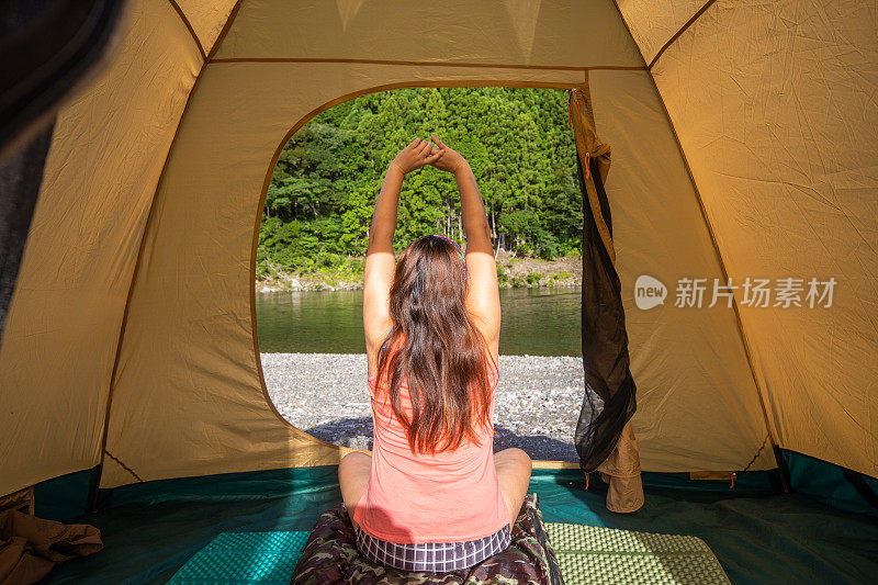 一个女人坐在帐篷里望着外面的湖