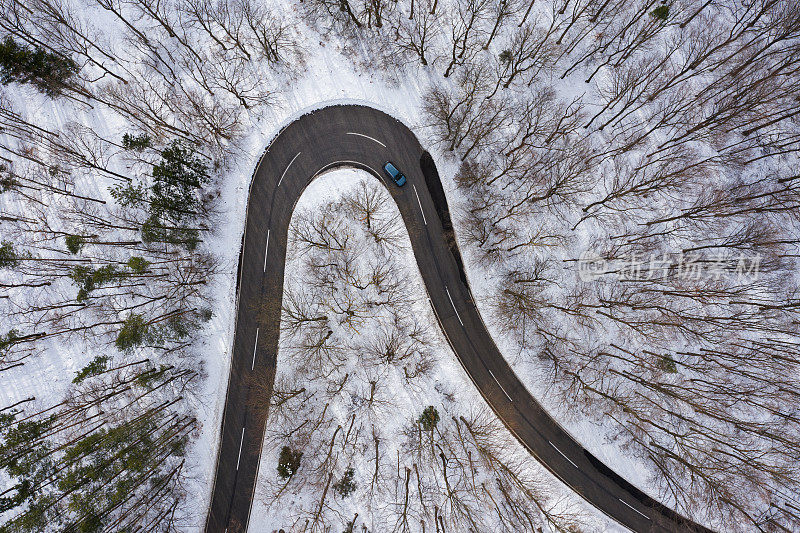 一条弯弯曲曲的乡村公路，穿过冬天积雪的森林