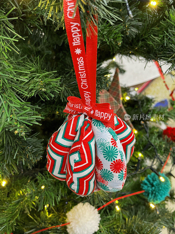 人造圣诞树树枝上手工制作的小饰物和折纸星星装饰的图像，绿色和白色的绒球的花环，绿色云杉针，模糊的白色精灵灯背景