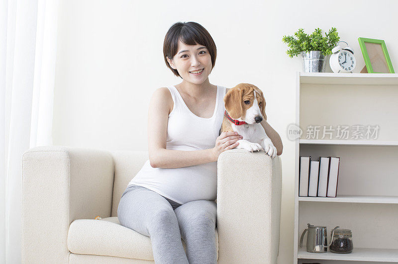 孕妇搂着宠物狗坐在沙发上微笑
