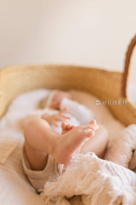 一个14周大的男婴的12个脚趾躺在一个舒适的奶油棉毯子在海草摩西篮子