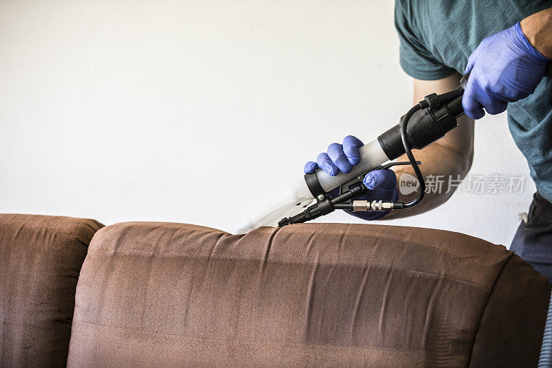 男子使用湿吸尘器清洁沙发