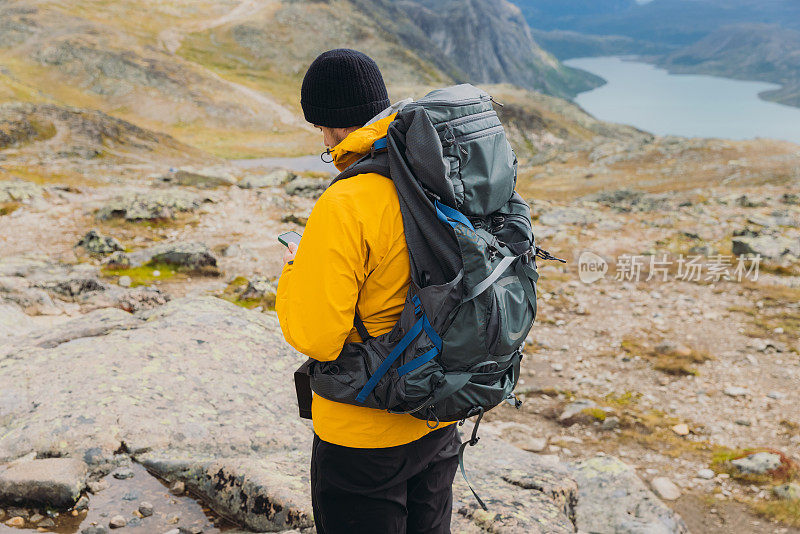 一名男子背着背包在挪威约顿海门国家公园登山时使用手机