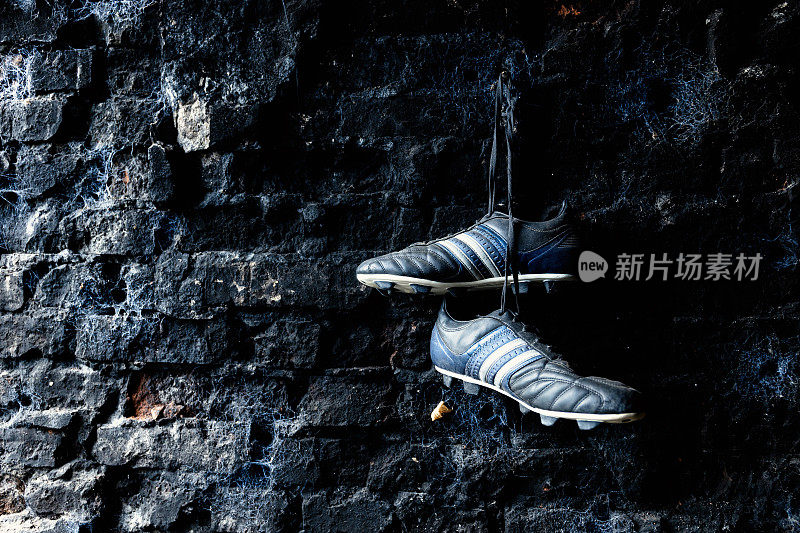 足球鞋挂在肮脏的砖墙上。