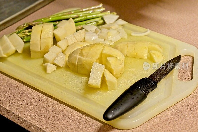 切好的土豆和芦笋放在砧板上，用削皮刀