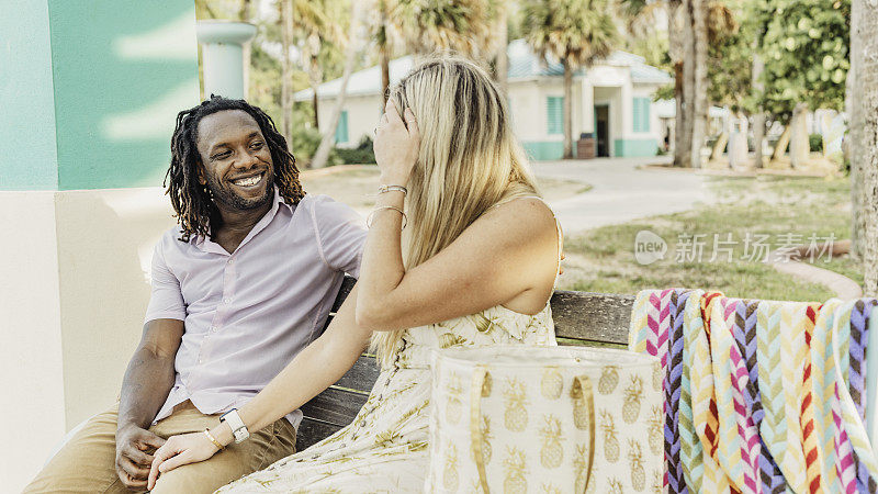 在阳光明媚的热带地区，快乐的夫妇在户外的夏日长凳上闲逛