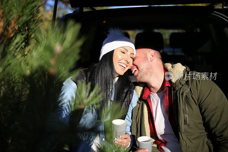 幸福的夫妇坐在汽车后备箱喝热茶库存照片