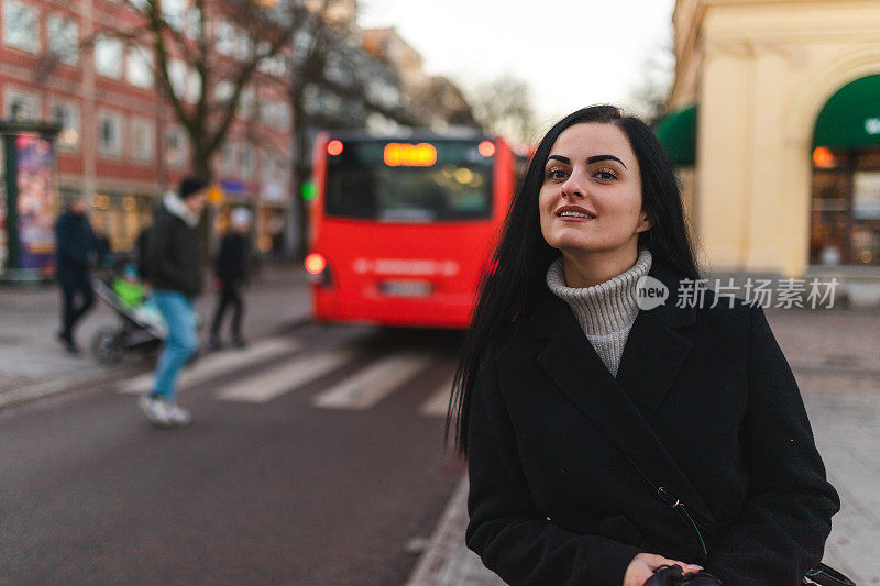 美丽的年轻女子在城市的公交车站等车