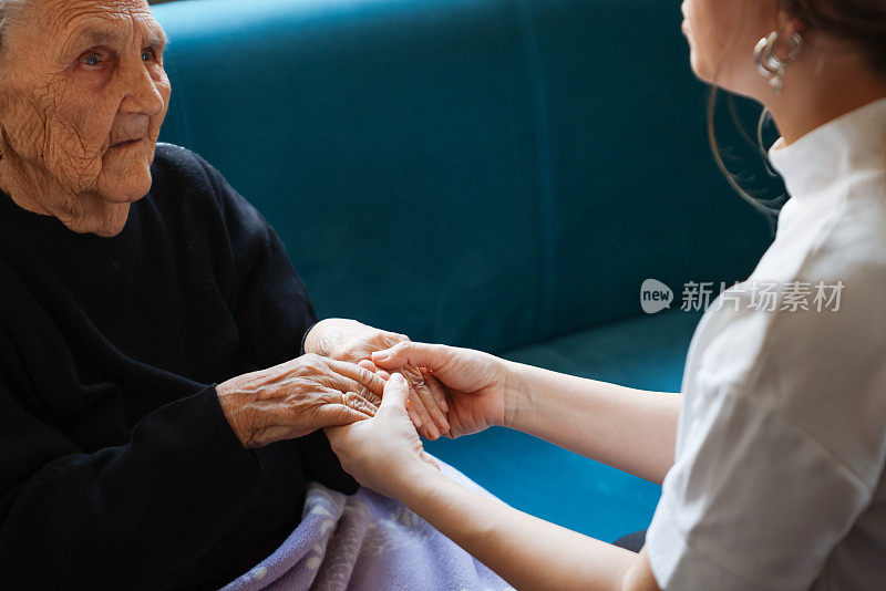 老女人的手牵着年轻女人的手，伸出援手，照顾老人的理念。