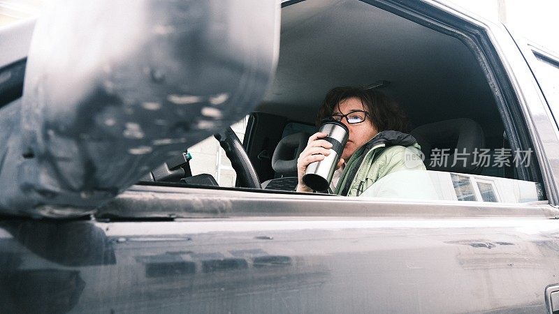 车上一个成熟的女人正在用旅行杯喝水