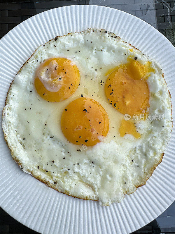 特写图像三个，合并，在煮熟的阳光面向上煎鸡蛋坐在白色，肋边盘，抬高视图