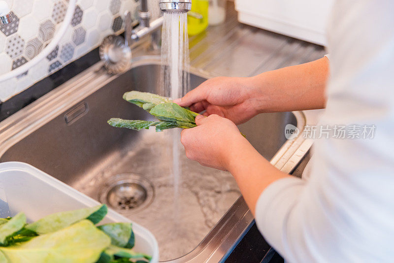 亚洲男人在水槽里洗菜。